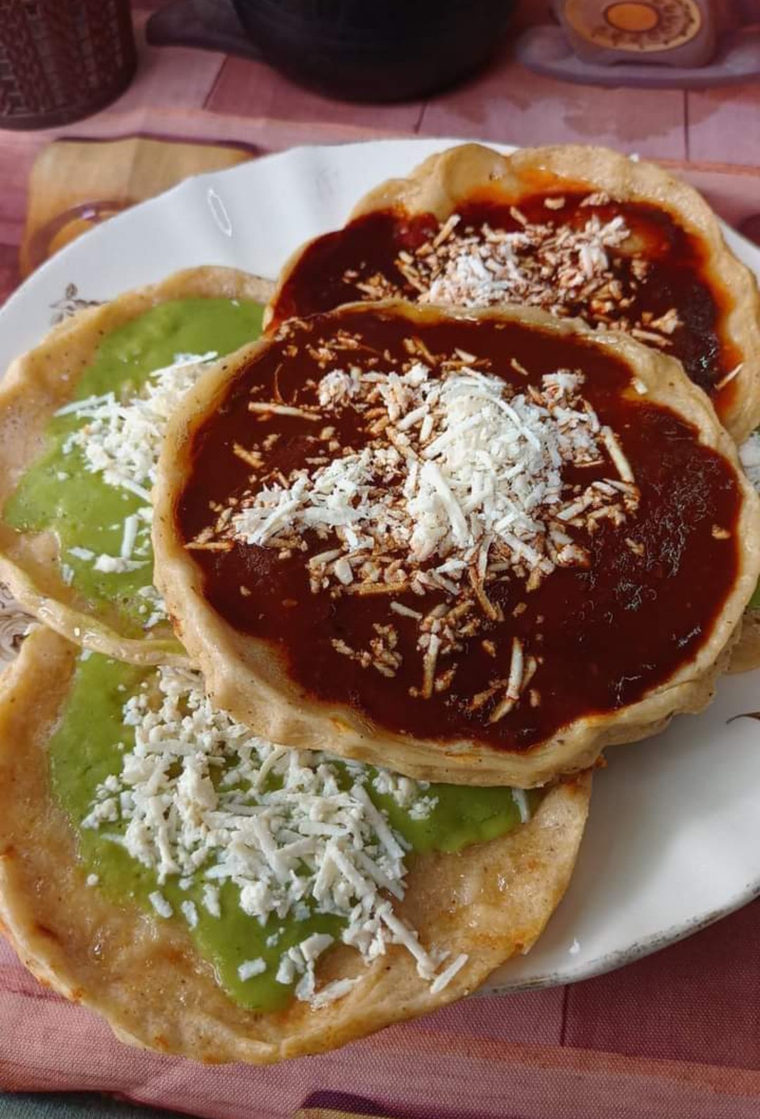 Three sopes topped with red and green salsa and grated cheese