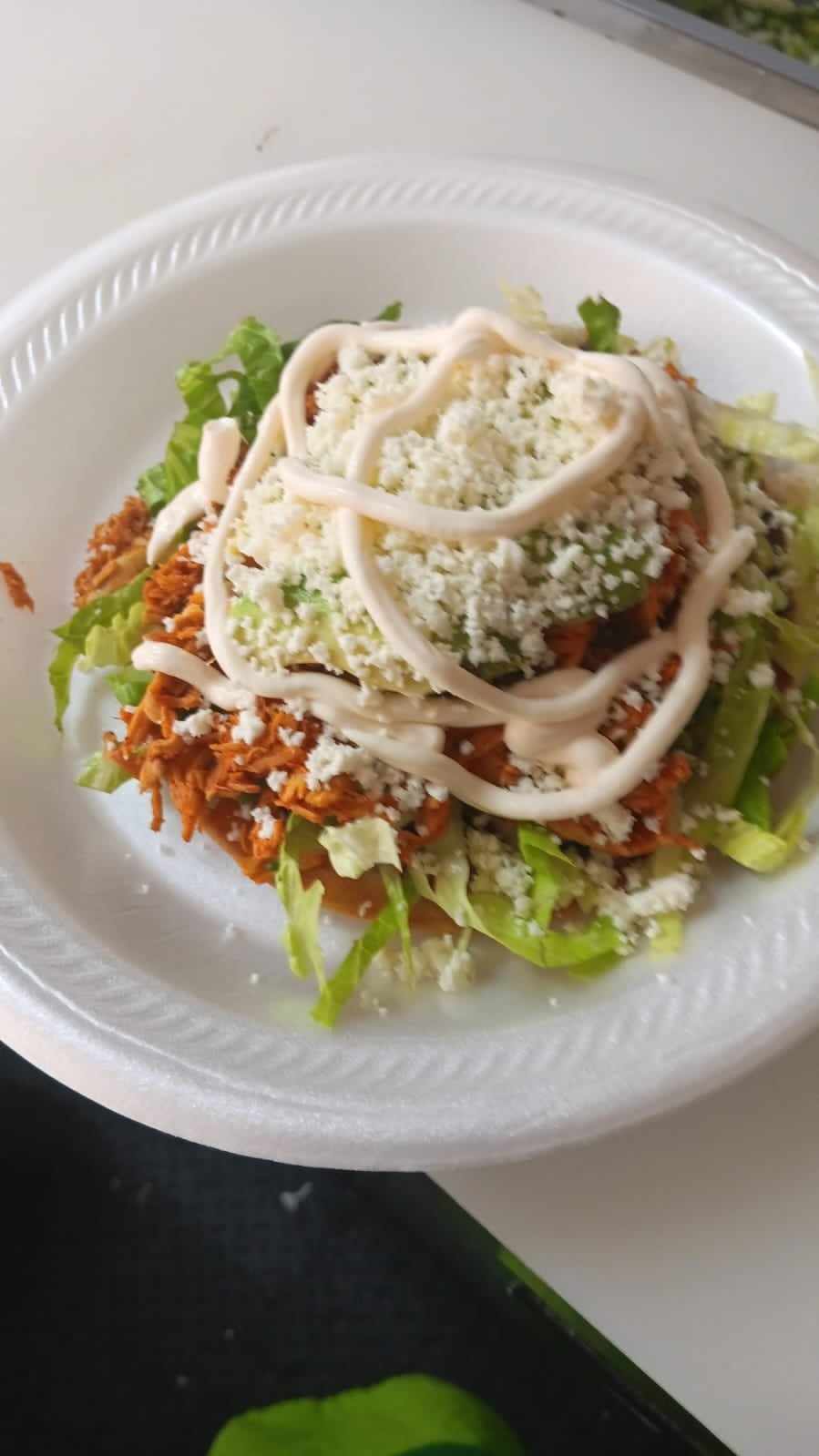 A plate of sopes with shredded meat, crema and fresh cheese